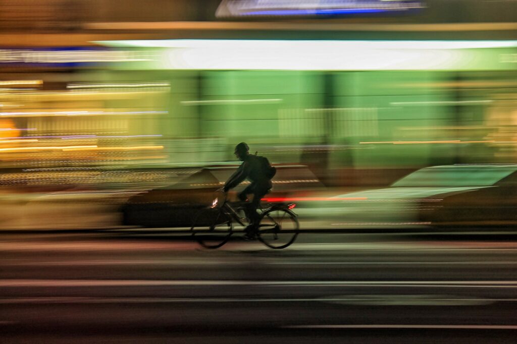men riding a bike in the city night with light tracks